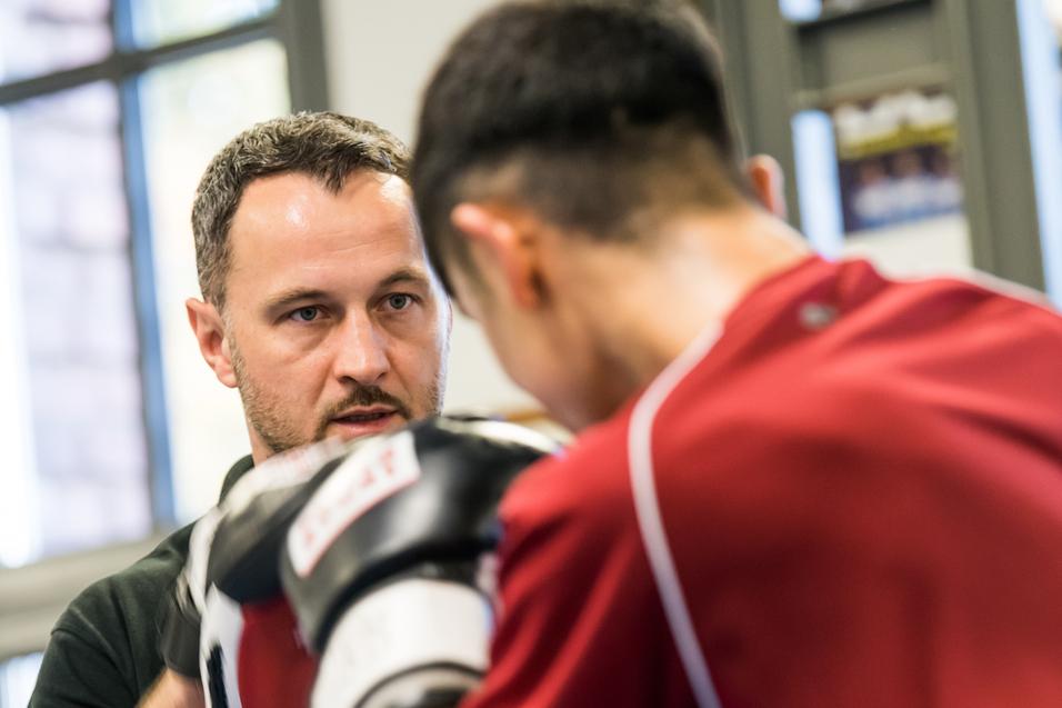 Trainer gibt Anweisungen an einen Boxschüler während einer Trainingseinheit in einem Fitnessstudio.